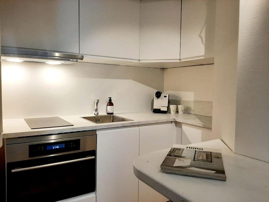 a kitchen with white cabinets and a sink and a stove at Top-floor studio, near park & sea, great transit in Helsinki