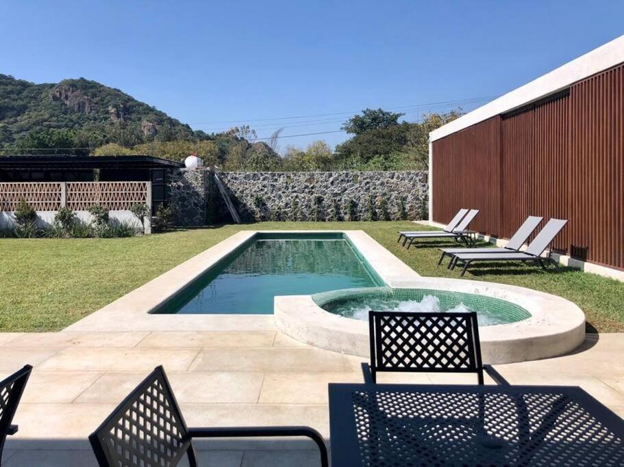 une cour avec une piscine, des chaises et une terrasse dans l'établissement Casa del ALMA., à Tepoztlán