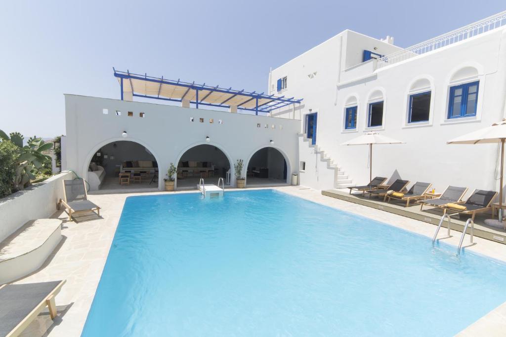 a swimming pool with chairs and a building at Hotel Semeli in Agios Prokopios