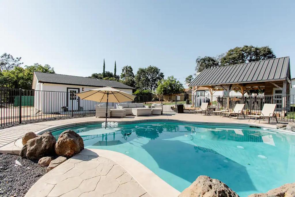 een zwembad met een patio en een parasol bij Beautiful spacious guest home in Roseville