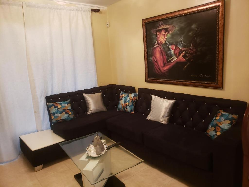 a living room with a black couch and a painting at Recidencial job in Santiago de los Caballeros