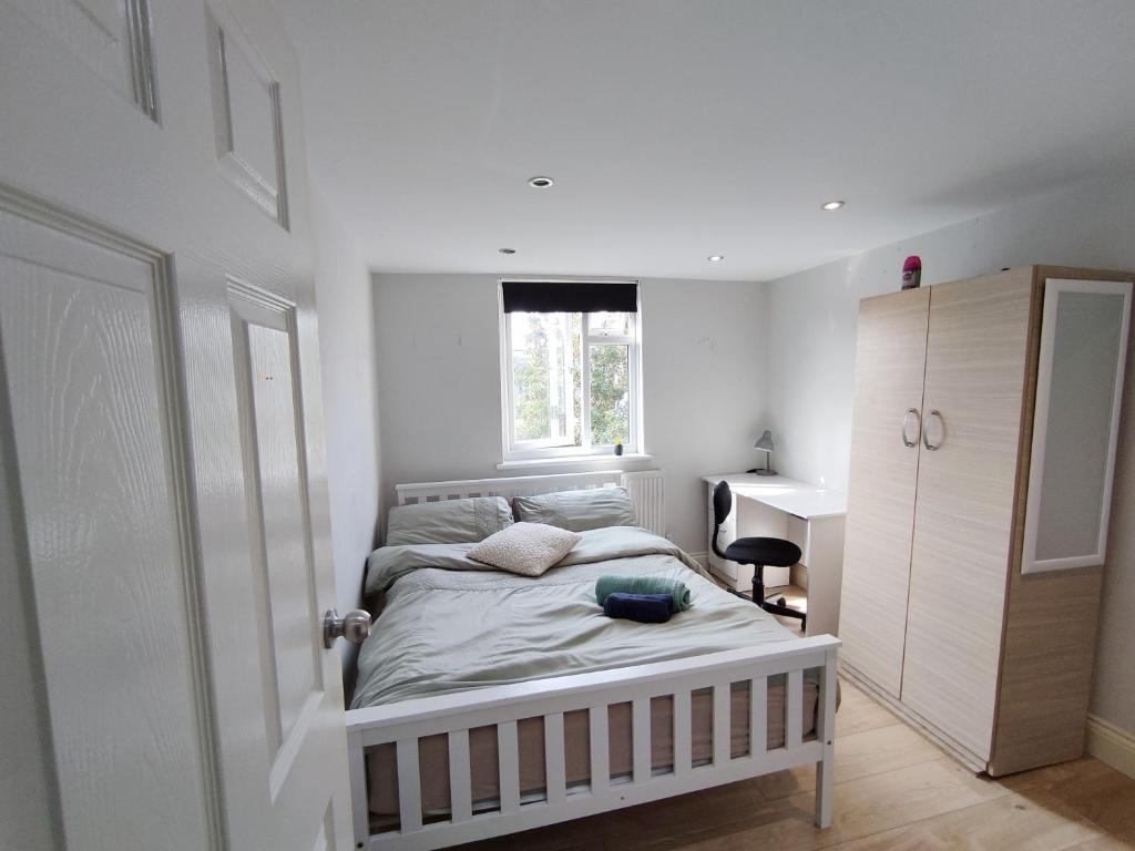 a bedroom with a bed with a desk and a window at Comfy Friendly Stay in London