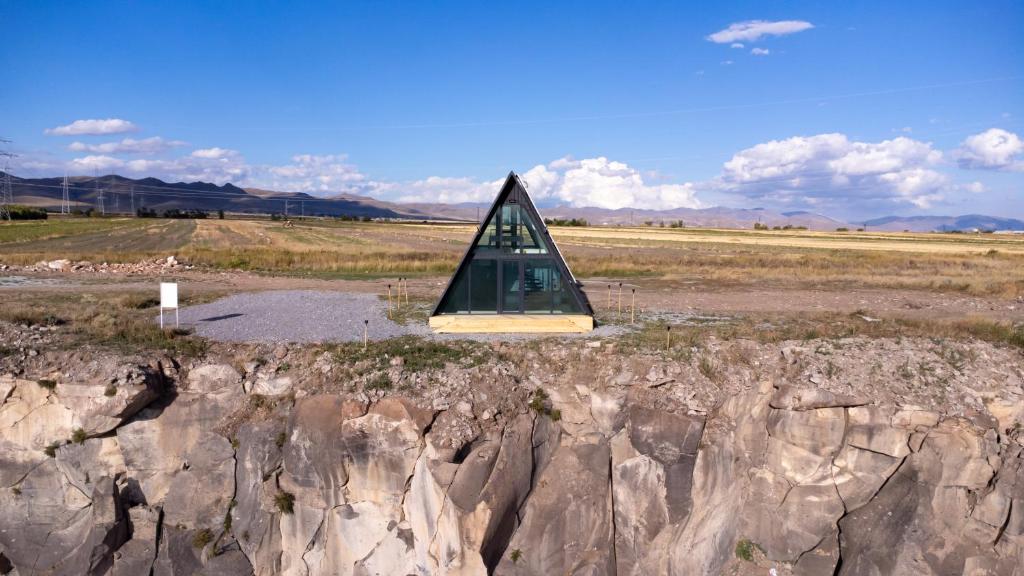 una piramide di vetro seduta sopra un campo roccioso di Chill With Tech 