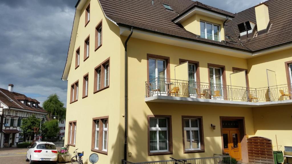 a yellow house with a car parked in front of it at Hotel Rössli in Basel
