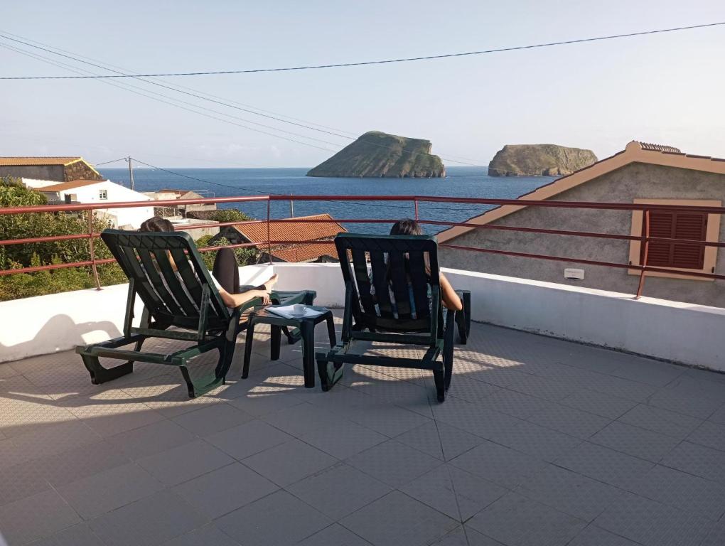 zwei Personen auf Stühlen auf einem Balkon mit Meerblick in der Unterkunft Casa da Canada da Fajã in Feteira