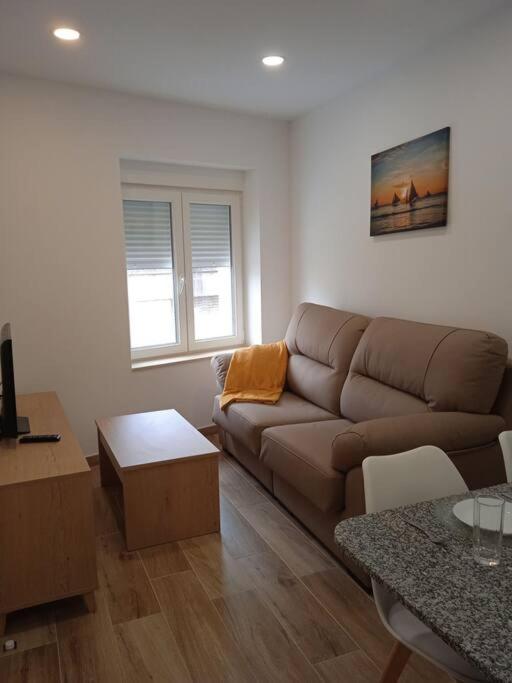 a living room with a brown couch and a table at La casa del Timón.Planta baja in Muros
