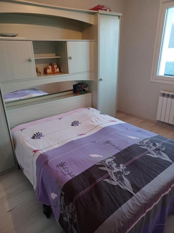 um quarto com uma cama com um cobertor roxo em Maison a phiphi em Ernée