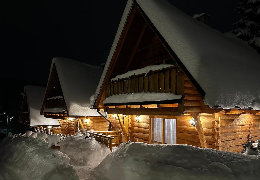 a log cabin covered in snow at night at Chałupy Na Brzyzku in Poronin