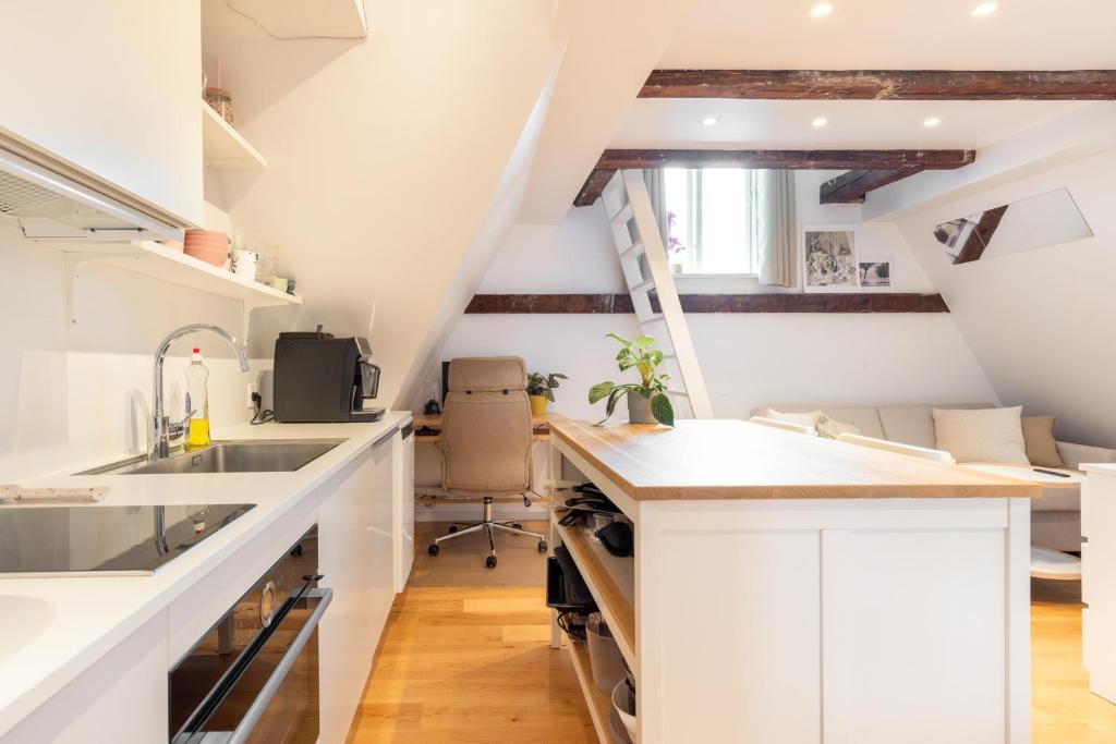 una cocina en el ático con armarios blancos y fregadero en Charming Loft City Center en Copenhague