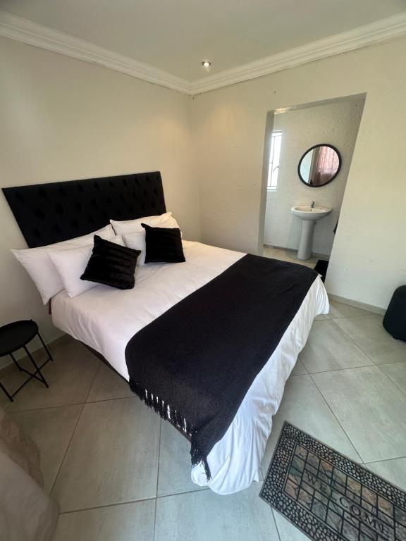 1 dormitorio con 1 cama grande con manta negra en Mphagahle B&B, en Mthenti