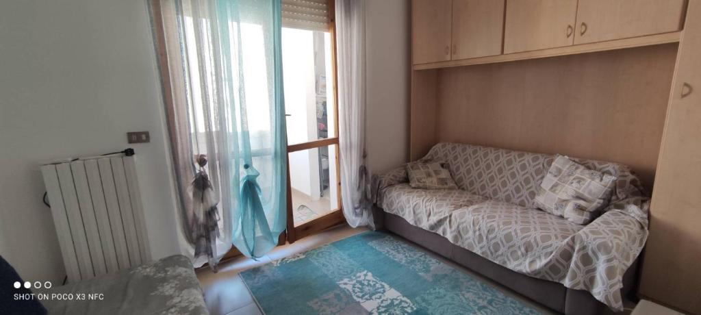 un piccolo soggiorno con divano e finestra di Da Serraona appartamento ad Alghero ad Alghero