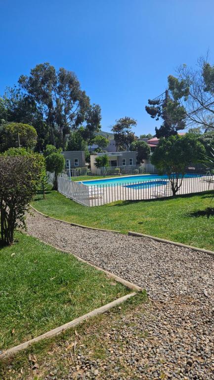 una cerca blanca junto a un patio con piscina en De Peppino Cabañas en Papudo