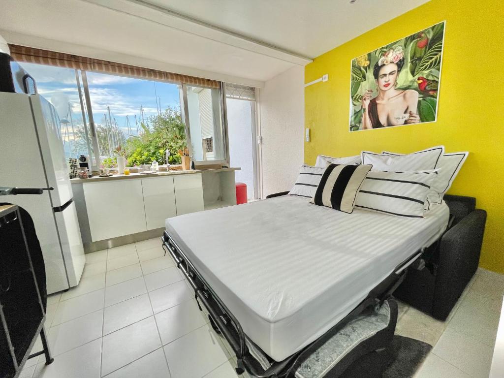 un grande letto in una stanza con parete gialla di Appartement Frida de la Marina a Les Trois-Îlets