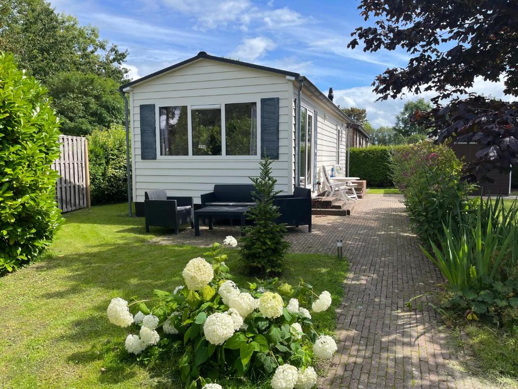 una casa pequeña en un jardín con patio en Rustig chalet 4 personen op recreatiepark de Friese Wadden Tzummarum buitenzwembad aanwezig op het park, en Tzummarum