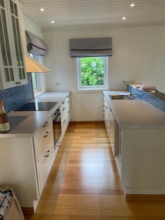 a large kitchen with white counters and a window at Charming coastal house with an ocean view in Garten