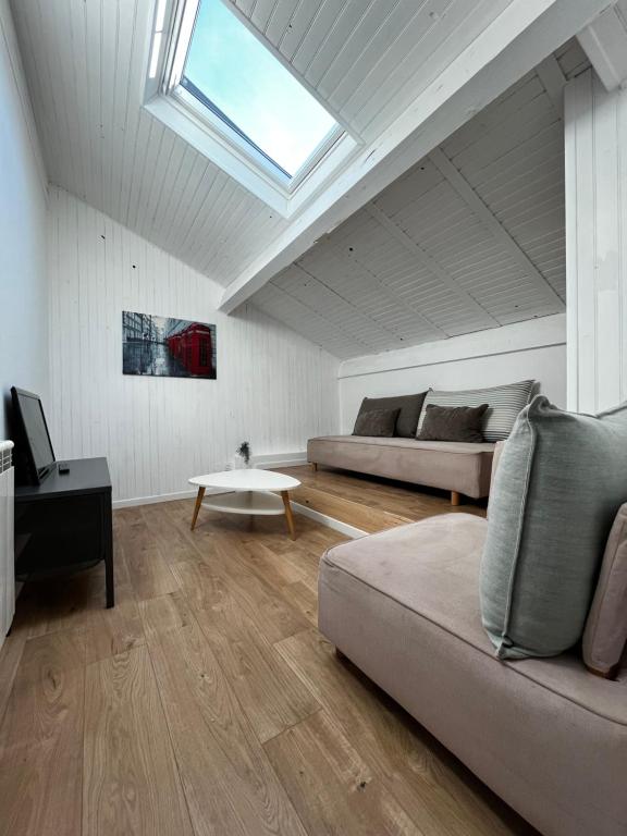 ein Wohnzimmer mit einem Sofa und einem Dachfenster in der Unterkunft Petite maison dans le beaujolais 