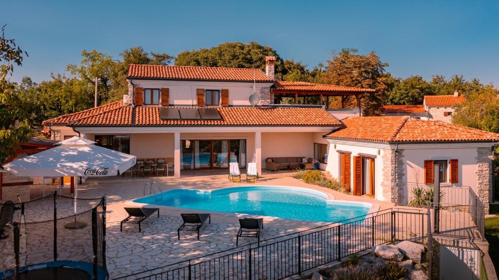 a villa with a swimming pool in front of a house at Villa Arton heated swimming-pool in Žminj