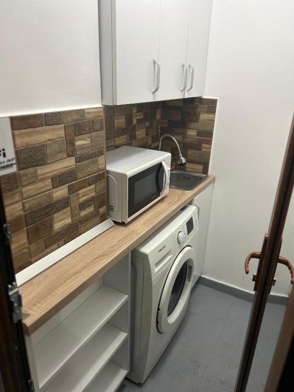 a small kitchen with a microwave and a washing machine at Apartament regim hotelier 1 camera in Galaţi
