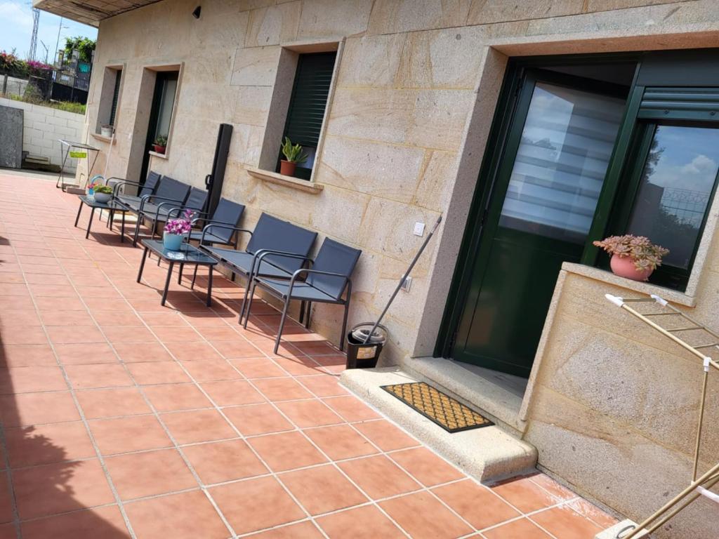 a patio with chairs and tables next to a building at Louridoplaya in Poio