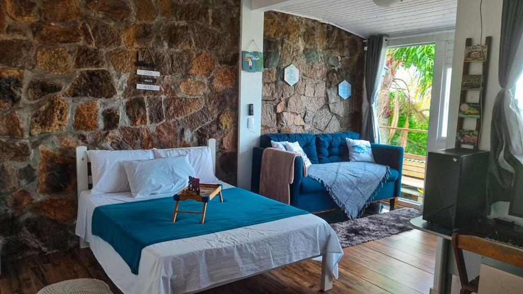 uma sala de estar com uma cama e uma parede de pedra em Loft Com Lago Hidro e Vista Para o Mar em Florianópolis