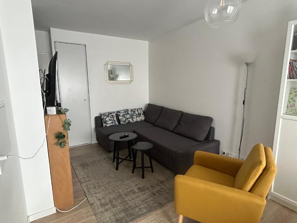 ein Wohnzimmer mit einem Sofa und einem Stuhl in der Unterkunft Appartement T2 -Parking -35Min Paris RER 2Min à Pied in Évry-les-Châteaux