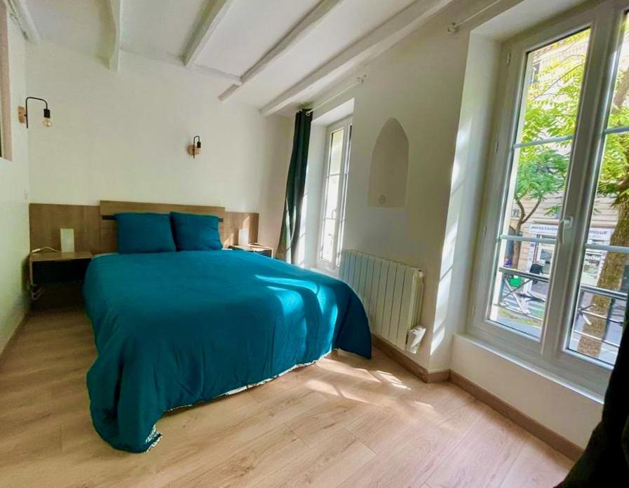 ein Schlafzimmer mit einem blauen Bett und einem Fenster in der Unterkunft Sydel2 in Paris