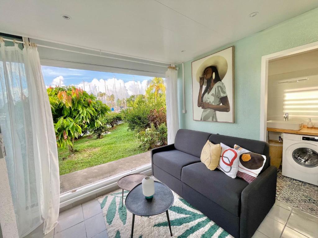 a living room with a couch and a large window at Appartement Belbo de la Marina in Les Trois-Îlets