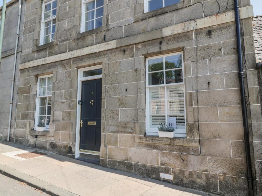 a brick building with a black door and windows at 6 Kirkstyle in Biggar