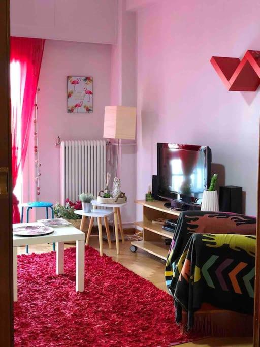 uma sala de estar com paredes cor-de-rosa e uma televisão em Boutique Apartment in the Center of Ioannina em Ioannina