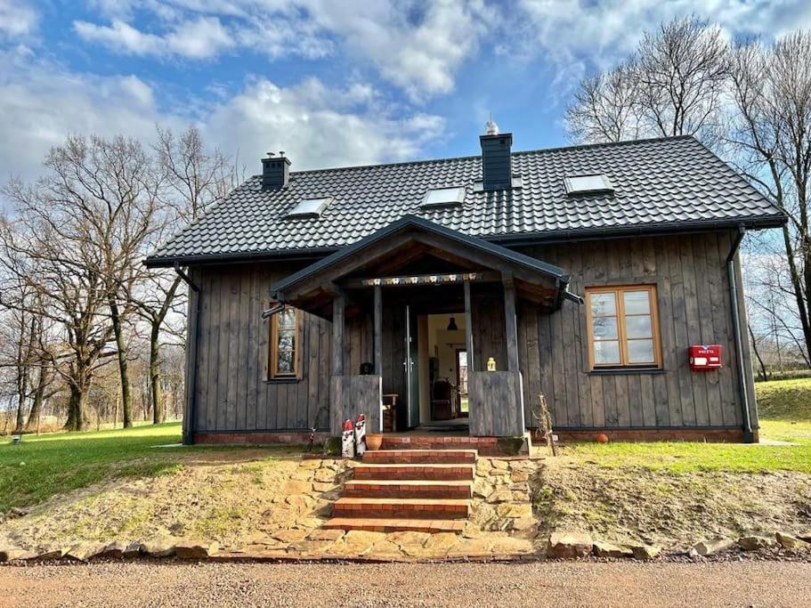 una pequeña casa de madera con una puerta principal y escaleras en Świętokrzyskie Stodoła Kasztanowa Aleja Radkowice, en Radkowice