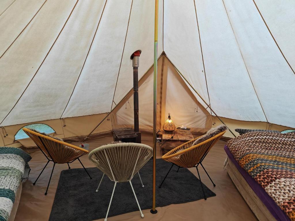 Au Pied Du Trieu, the glamping experience في Labroye: خيمة مع كراسي وسرير وطاولة