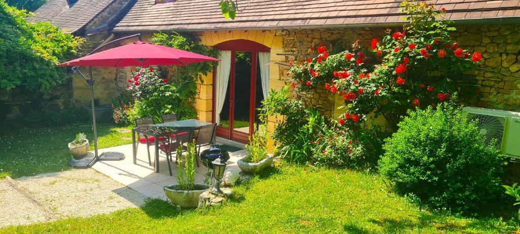 a house with a table and an umbrella in the yard at Coquelicots Dordogne in Saint-Julien-de-Lampon
