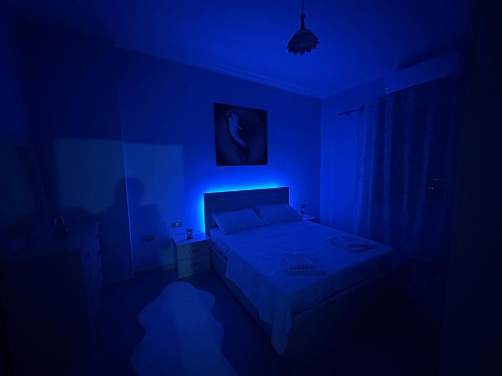 Habitación azul con cama y luz azul en Moonlight Apartment, en Shkodër