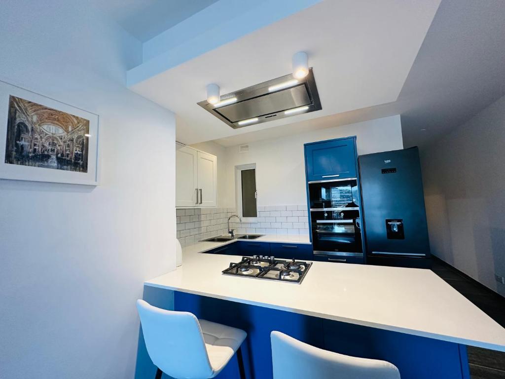 uma cozinha com um balcão branco e armários azuis em Del Mar Apartment! em Żebbuġ