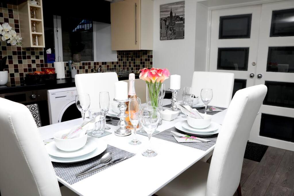 The Cosy Corner 2 Bedroom flat في شيفيلد: طاولة بيضاء مع كراسي بيضاء وطاولة بيضاء مع ورود