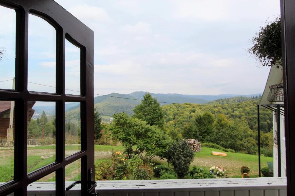 an open window with a view of a field and mountains at Котедж "Красний Краєвид" in Yaremche
