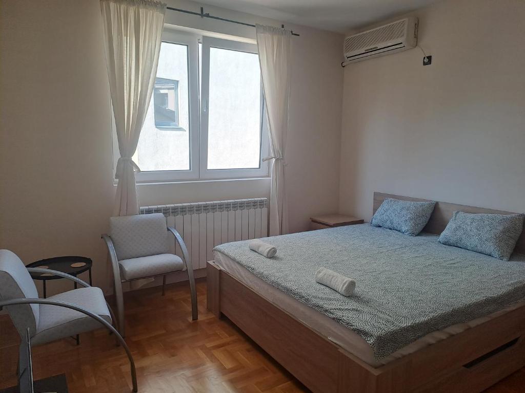 een slaapkamer met een bed, een stoel en een raam bij Apartman Quality in Voždivac