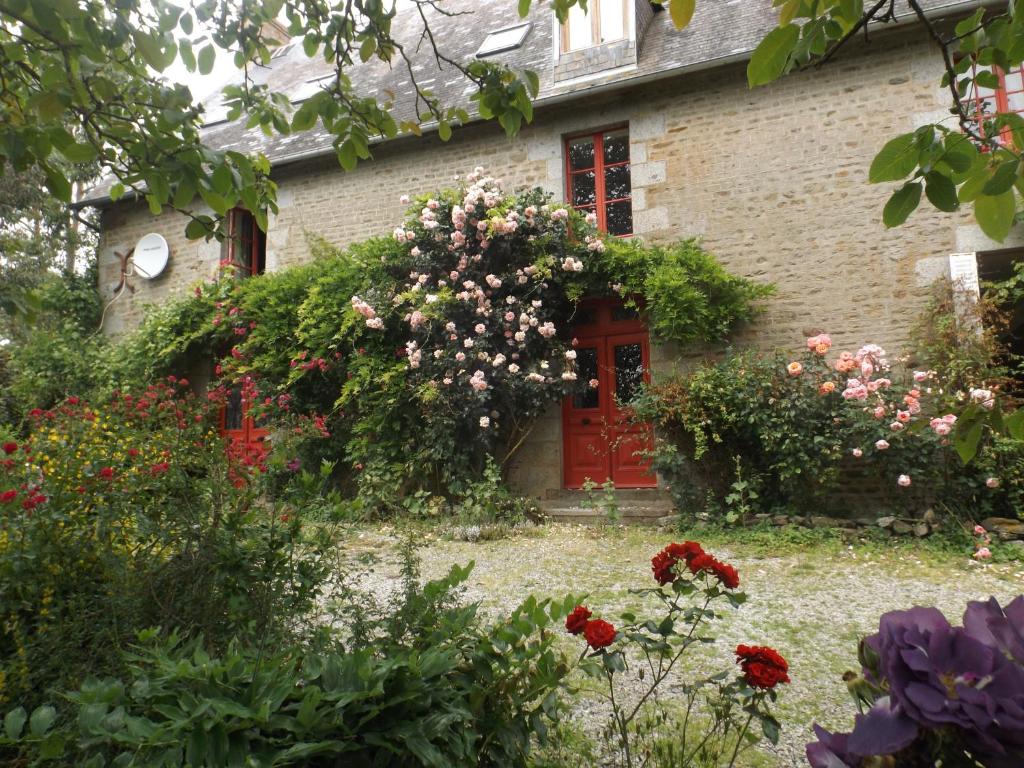 ein Backsteinhaus mit einer roten Tür und Blumen in der Unterkunft Le Grand Pont in Estry