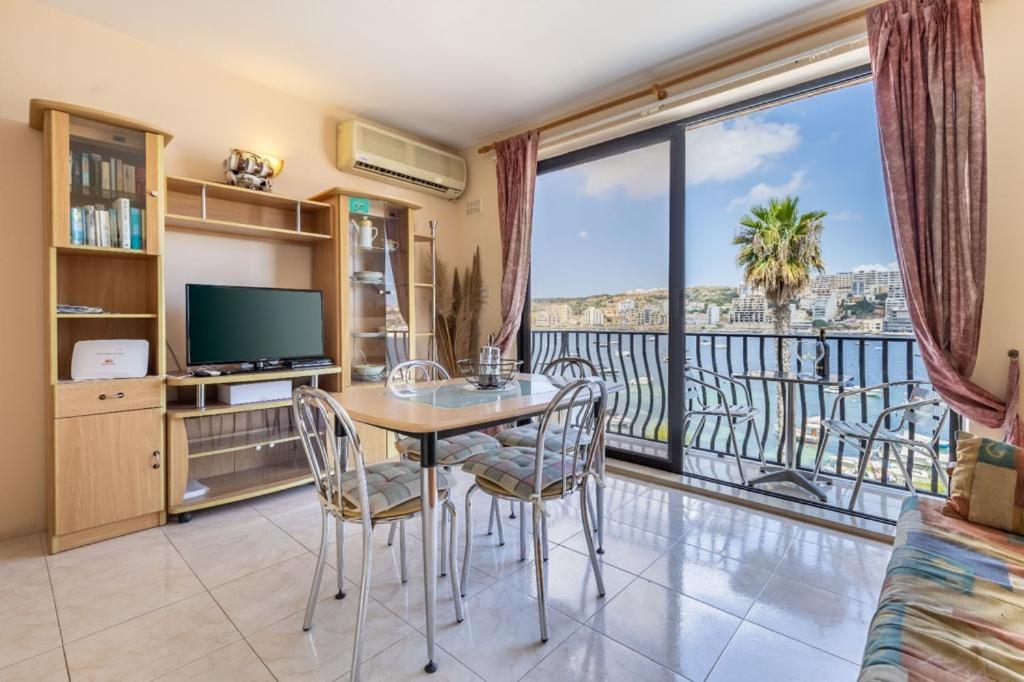 a dining room with a table and chairs and a balcony at Nice seaview apt at St Paul's Bay in St. Paul's Bay