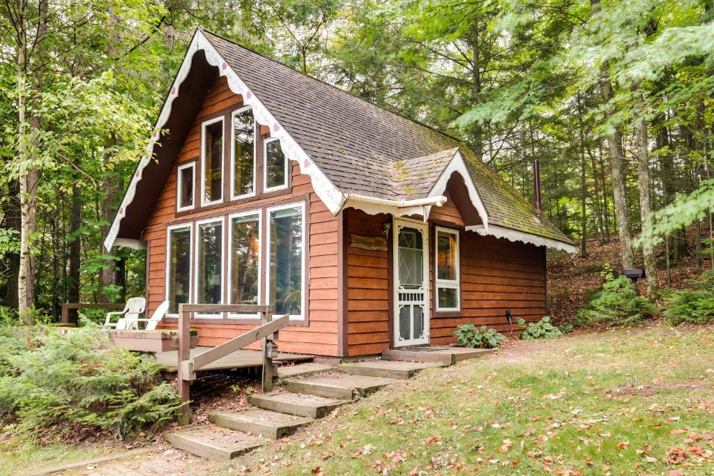 eine kleine Hütte im Wald mit einer Veranda in der Unterkunft Lakefront Ogema Vacation Rental Cabin with Fire Pit! 