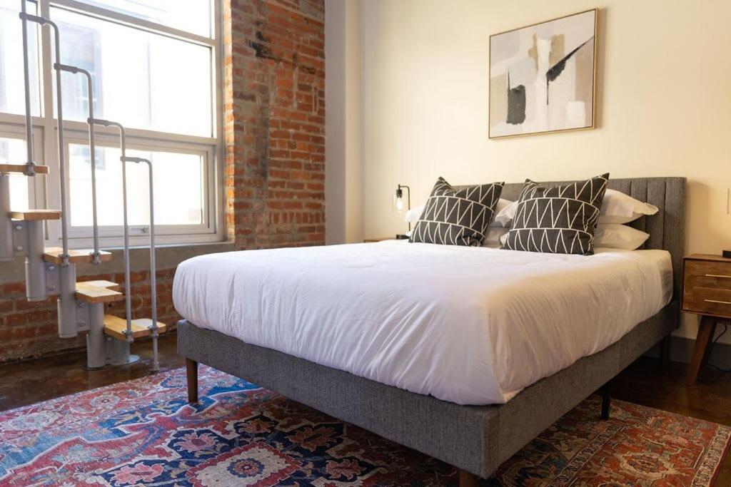 Un dormitorio con una cama grande con almohadas. en Historic 1 Br Apt With Exposed Brick Loft Downtown, en Roanoke