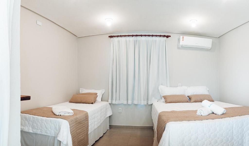 two beds in a room with a window at Pousada Estrela do Mar in Barra Grande