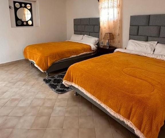 um quarto com 2 camas e cobertores cor-de-laranja em Hotel Don Quijote em Mineral de Pozos