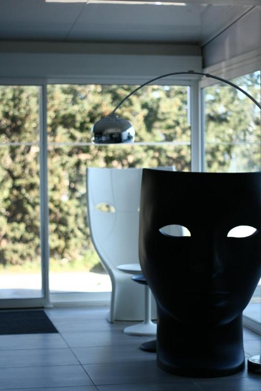 a black mask sitting in a room with a lamp at Hôtel L&#39;Escale Coté Port in LʼÎle-Rousse