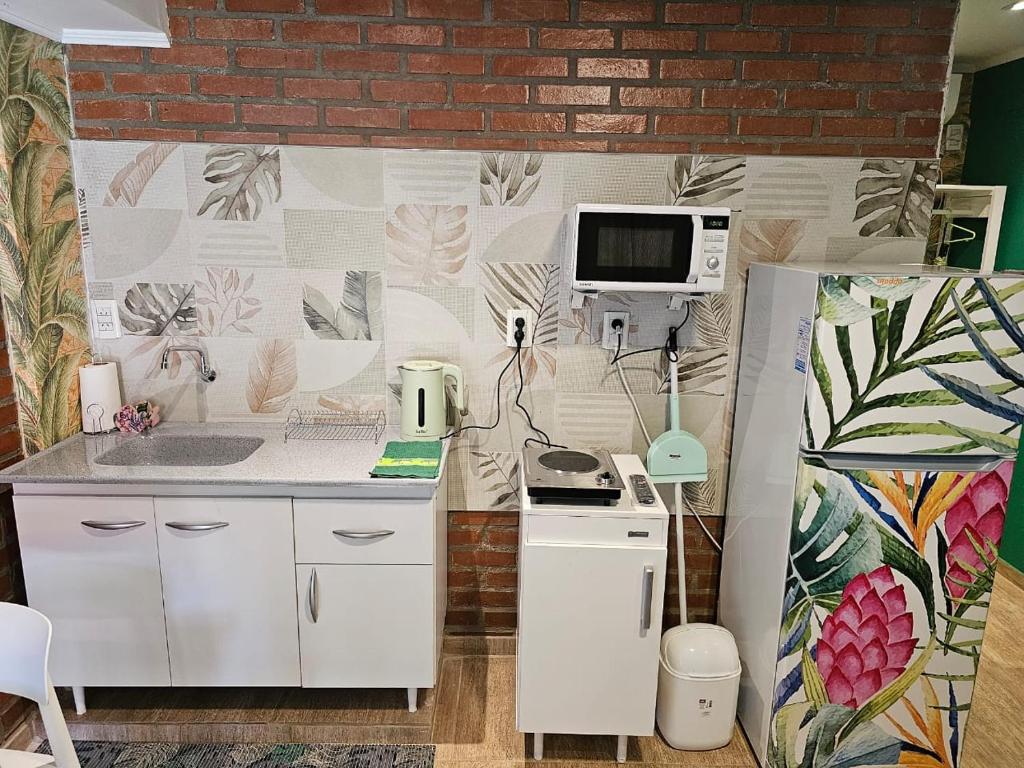 a kitchen with white cabinets and a wall with a mural at Casa 24 Puerto Iguazu in Puerto Iguazú