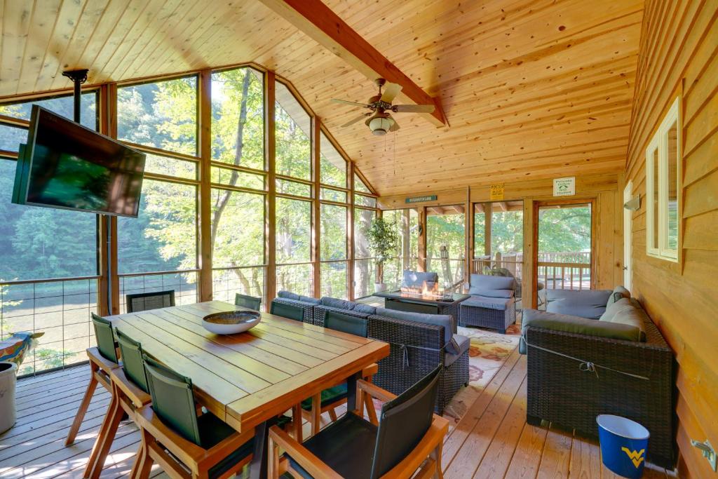 Riverfront West Virginia Cabin with Screened-In Deck في Marlinton: غرفة معيشة مع طاولة وكراسي وتلفزيون