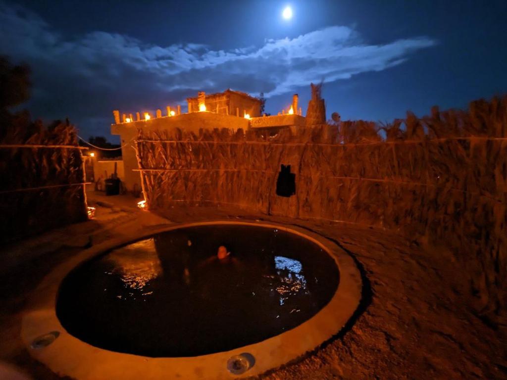 a stone wall with a fountain in front of a castle at night at Friendo's House & Hot Spring in Siwa