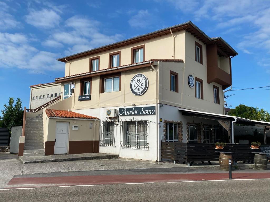 a building with a clock on it on a street at Hostal La Concha in Somo