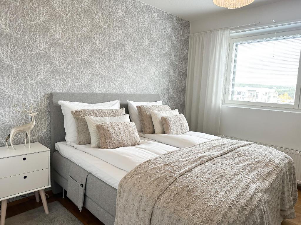 um quarto com uma cama grande com lençóis brancos e uma janela em Aurora Penthouse em Rovaniemi