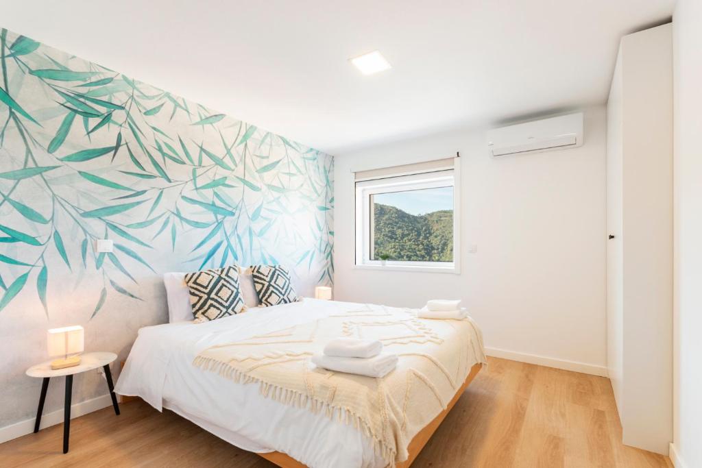 a bedroom with a bed with a tropical mural on the wall at Loriga View Apartments in Loriga